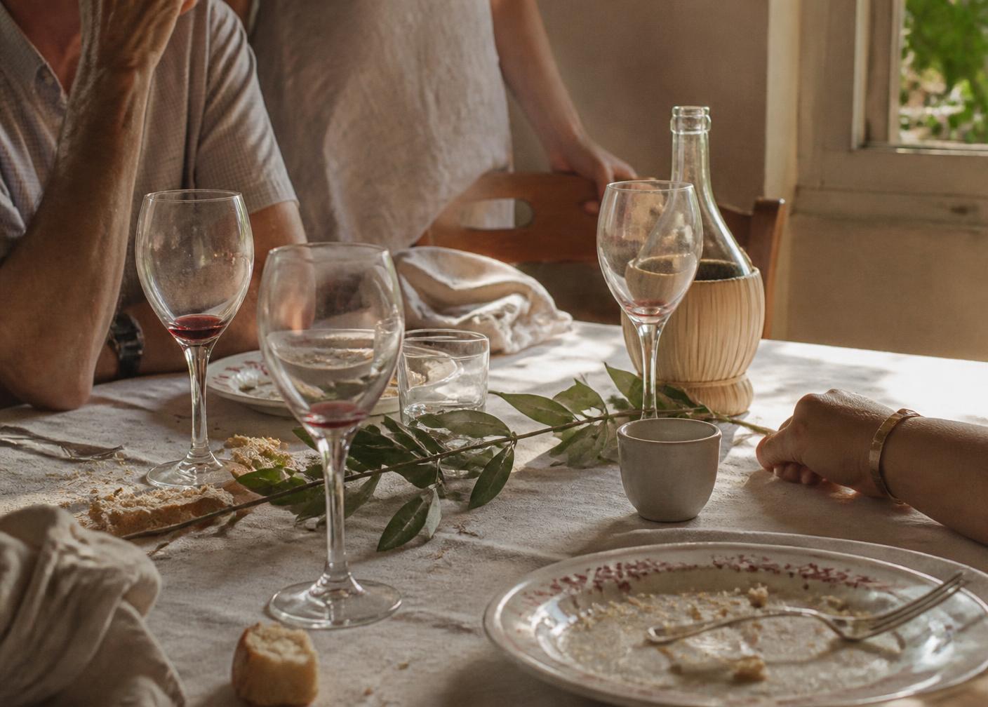 Bord etter en lang lunsj med linduk, glass og olivengren